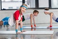 Cute sporty kids exercising on yoga mats in gym and smiling