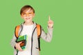 Cute student boy with school bag over green background. Happy kid in glasses pointing up on empty copy space Royalty Free Stock Photo