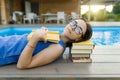 Cute student girl reading book lying near the pool. Education, summer, knowledge Royalty Free Stock Photo