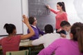 Cute student girl solves task near blackboard