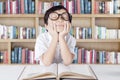 Cute student with glasses daydreaming in library Royalty Free Stock Photo