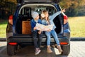 Agreeable boy and girl are looking at the road map while sitting in the auto`s trunk and discussing the move direction Royalty Free Stock Photo