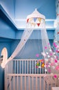 Cute stylish designed interior of baby room with wooden crib, mo