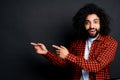 Cute stylish guy with afro hairstyle looks at the camera and points his fingers to the side Royalty Free Stock Photo