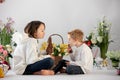 Cute stylish toddler child and older brother, boys with white shirt, playing with eggs and chocolate bunny on Easter decoration Royalty Free Stock Photo