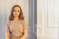 A cute stylish young girl is sitting in the doorway of her room. Teenager. Sadness