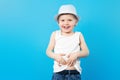 Cute summer boy in white t-shirt and hat on a blue background with copy space. Summer child