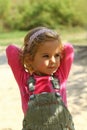 Cute sunlit toddler girl in pink posing hands behind head outdoor