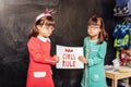 Cute sunny children standing near the blackboard with sign girls rule