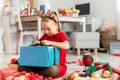 Cute super excited young girl opening large christmas present while sitting on living room floor. Candid family christmas time. Royalty Free Stock Photo