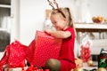 Cute super excited young girl opening large red christmas present while sitting on living room floor. Candid family christmas time Royalty Free Stock Photo