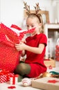 Cute super excited young girl opening large red christmas present while sitting on living room floor. Candid family christmas time Royalty Free Stock Photo