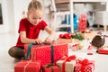 Cute super excited young girl opening large red christmas present while sitting on living room floor. Candid family christmas time Royalty Free Stock Photo