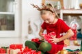 Cute super excited young girl opening large red christmas present while sitting on living room floor. Candid family christmas time Royalty Free Stock Photo