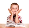 Cute surprised boy sitting at table on book, globe isolated. Royalty Free Stock Photo