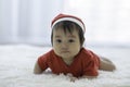 Cute Sweet Adorable Asian Baby wearing Santa hat and cloth costume lying on white carpet Royalty Free Stock Photo