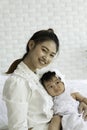 Cute Sweet Adorable Asian Baby wearing white dress sitting on Carpet smiling and playing with Beauty mother happiness