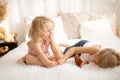 Cute sweet toddler children, tickling feet on the bed, laughing and smiling