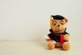 Cute teddy bear with nice graduation clothes and diploma on wooden table. School concept Royalty Free Stock Photo
