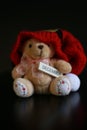 Cute teddy bear with red christmas hat isolated on dark black background. Royalty Free Stock Photo