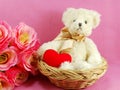 Cute teddy bear with red heart in the basket with pink background Royalty Free Stock Photo