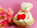 Cute teddy bear with red heart in the basket with pink background Royalty Free Stock Photo
