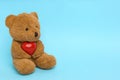 Cute teddy bear with red heart on light blue background, space for text. Valentine`s day celebration Royalty Free Stock Photo