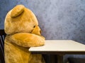 Cute teddy bear sit on the chair in front of dining table. Make it seem like waiting for favorite dish