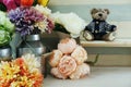 Teddy bear sitting on wooden table with artificial flower home decoration