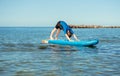 Cute teen boy making yoga on SUP boars in Baltic sea.