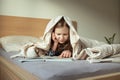Cute teen child girl lying and reading book on bed under the blanket Royalty Free Stock Photo