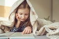 Cute teen child girl lying and reading book on bed under the blanket Royalty Free Stock Photo