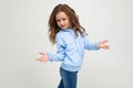 Cute teen girl in a blue hoodie indignant waving hands on a white background