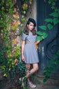 Cute teen girl in dress and black beret retro style look outdoor near old metal door and colorful creeper around