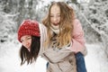 Cute teen girl and her mother having fun on a walk in snow covered pine forest on chilly winter day. Teenage child exploring Royalty Free Stock Photo