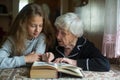 Cute teen girl with her old grandmother reading a book Royalty Free Stock Photo