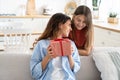 Cute teen girl daughter congratulating happy young mother with birthday at home, give her gift box Royalty Free Stock Photo