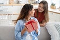 Cute teen girl daughter congratulating happy young mother with birthday at home, give her gift box Royalty Free Stock Photo