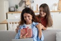 Cute teen girl daughter congratulating happy young mother with birthday at home, give her gift box Royalty Free Stock Photo