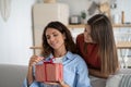 Cute teen girl daughter congratulating happy young mother with birthday at home, give her gift box Royalty Free Stock Photo