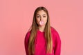 Cute teen girl in pink hoodie, blows bubble of chewing gum Royalty Free Stock Photo