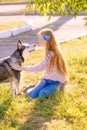 Cute teen girl with red long hair walks with her husky breed dog in the autumn park. Children and dogs.