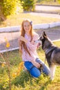 Cute teen girl with red long hair walks with her husky breed dog in the autumn park. Children and dogs. Royalty Free Stock Photo