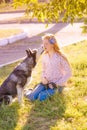 Cute teen girl with red long hair walks with her husky breed dog in the autumn park. Children and dogs.