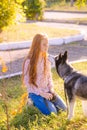 Cute teen girl with red long hair walks with her husky breed dog in the autumn park. Children and dogs.