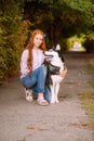 Cute teen girl with red long hair walks with her husky breed dog in the autumn park. Children and dogs. Royalty Free Stock Photo