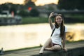 Cute teen girl takes a selfie on her phone while sitting on the city embankment. Royalty Free Stock Photo