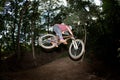 Cute teen jumping with his bike over a natural ramp in the fores Royalty Free Stock Photo