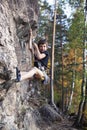 Cute teen kid climbing on rock with insurance, lifestyle sport people concept Royalty Free Stock Photo