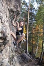 Cute teen kid climbing on rock with insurance, lifestyle sport people concept Royalty Free Stock Photo